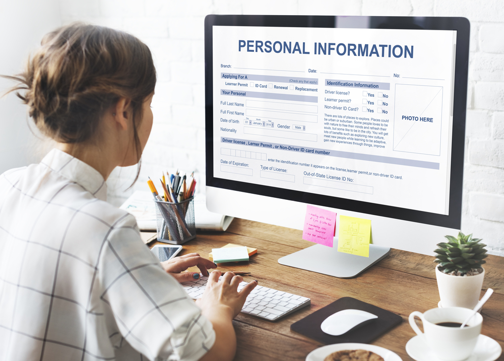 woman, appears to be, white or brown skin, working at desk, facing computer screen that says, "personal information"