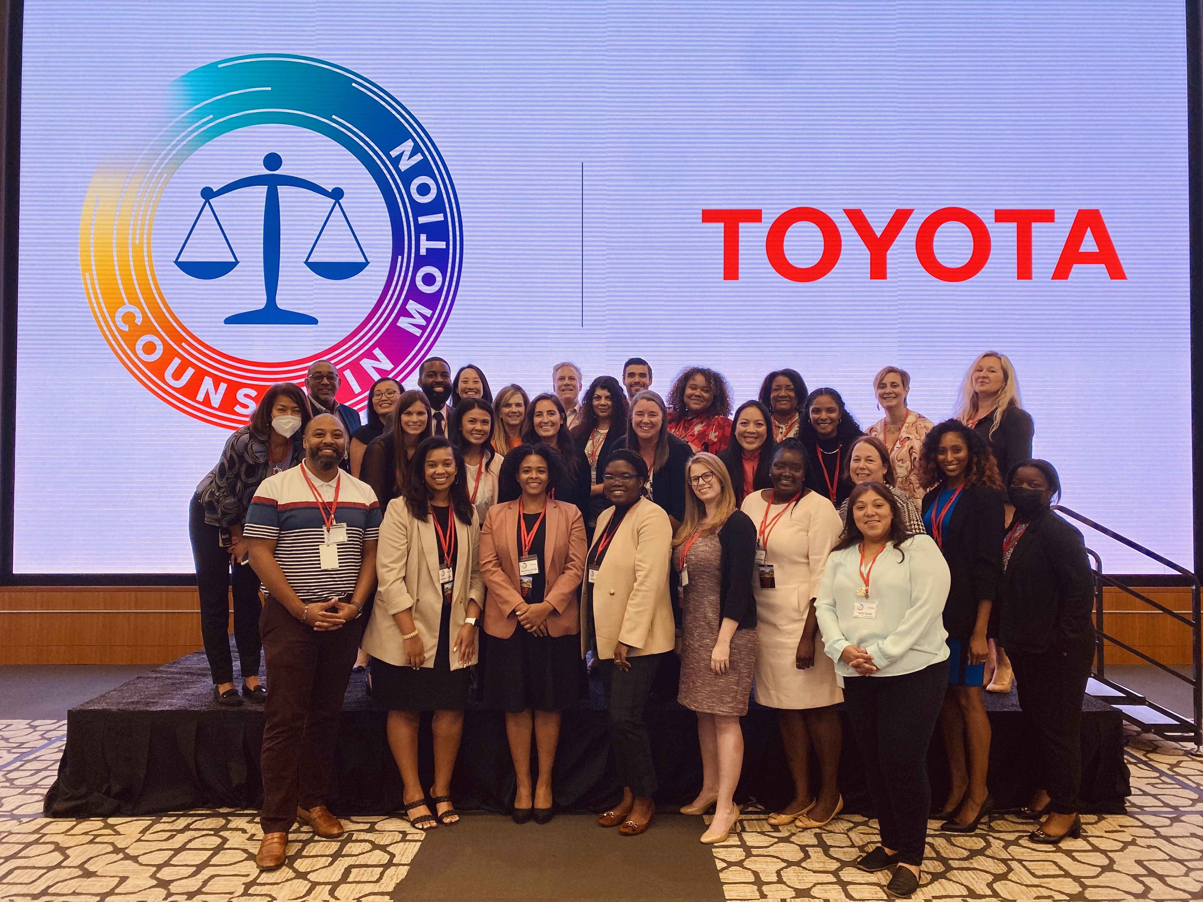 Group of attendees gathered in front of a sign for Toyota's DEI Counsel in Motion event.