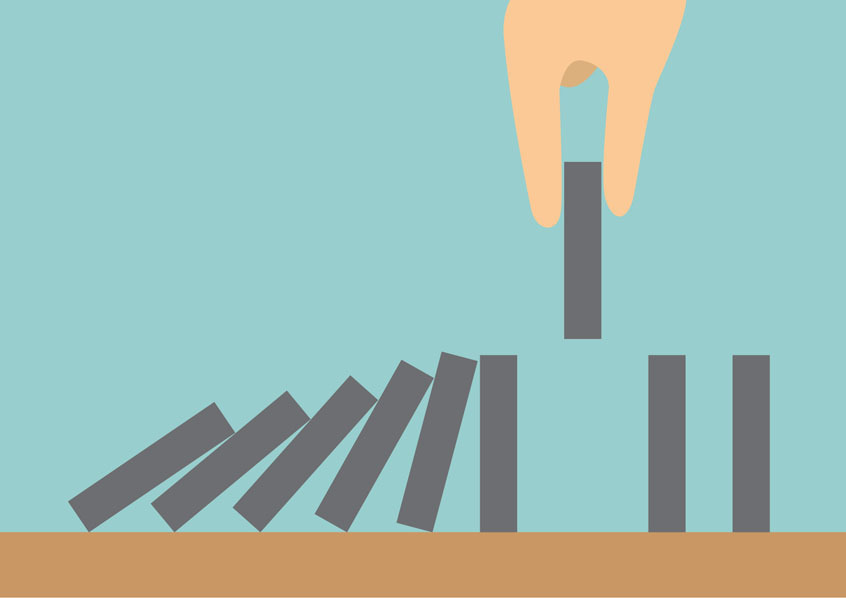 a hand preventing a line of dominoes from collapsing