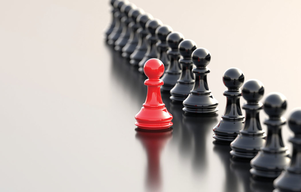 red chess piece standing out from black chess pieces