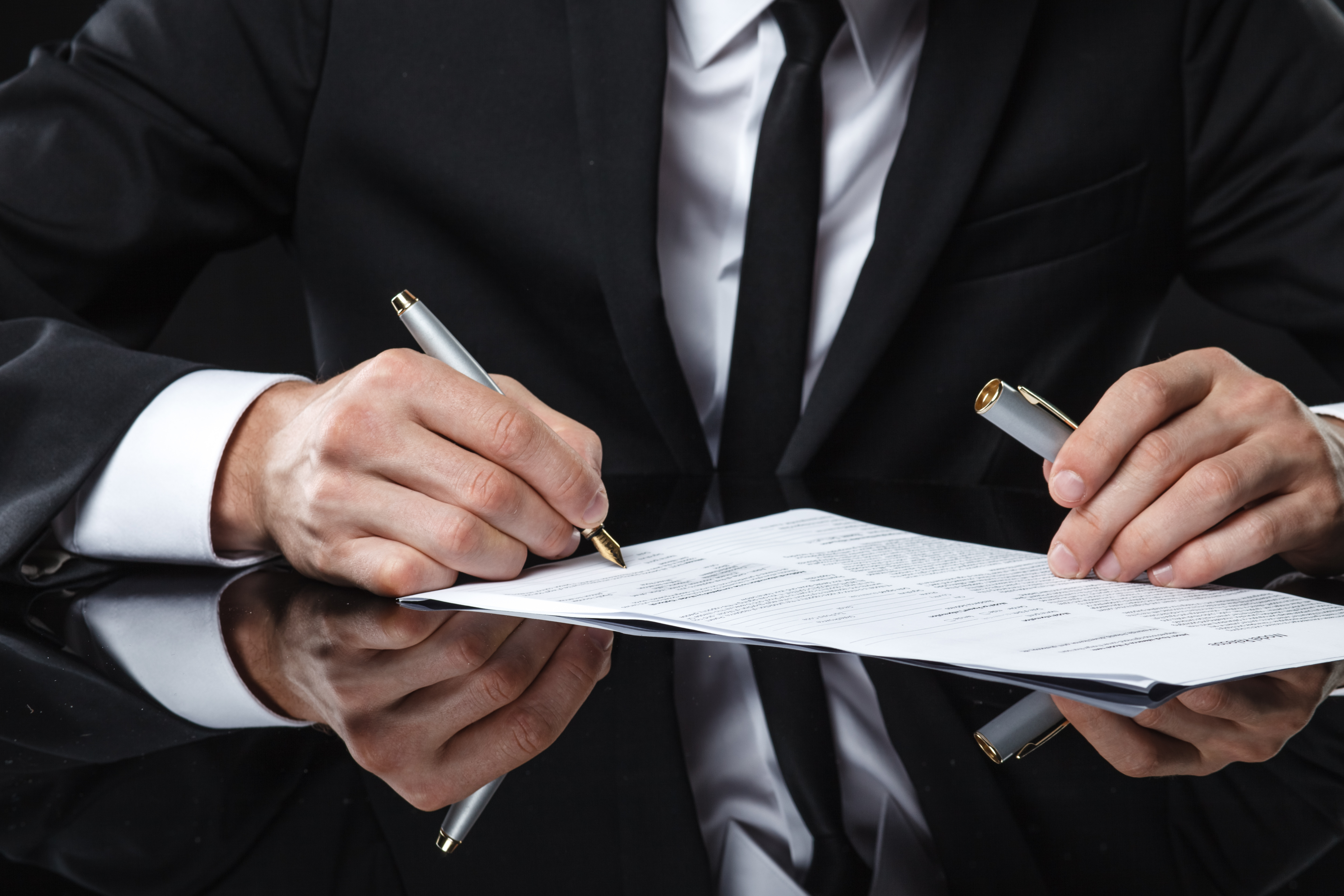 A man in a suit signing a document.