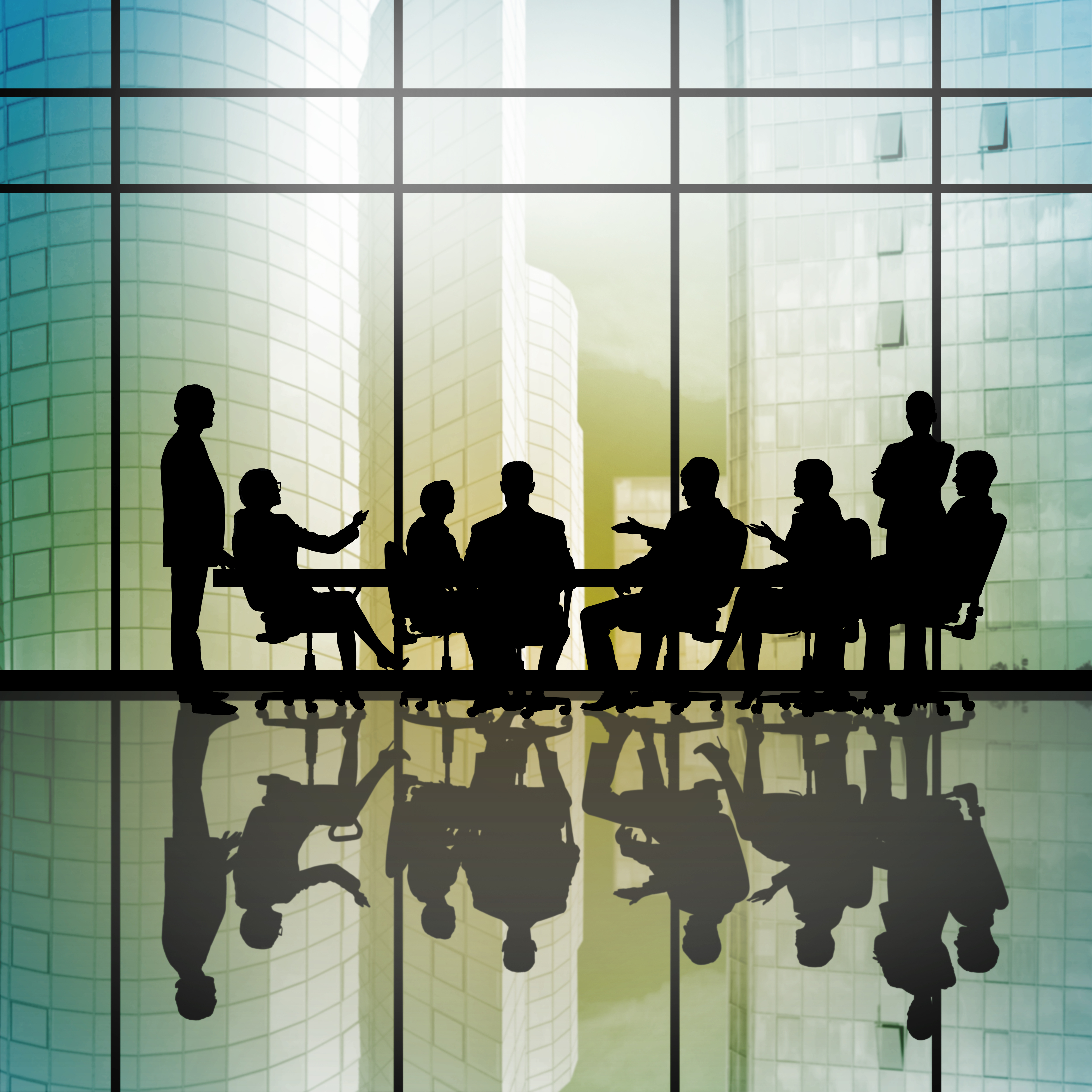 Silhouttes of business people as team sitting round table.