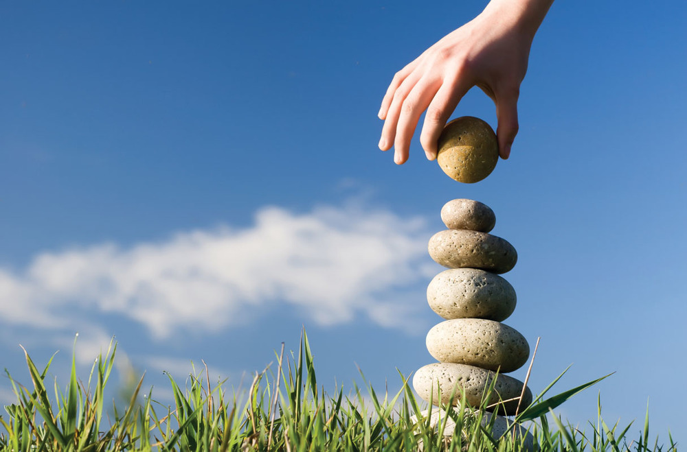 a hand building a stack of stones