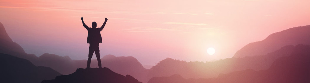 Person with both hands in the air at the top of a mountain