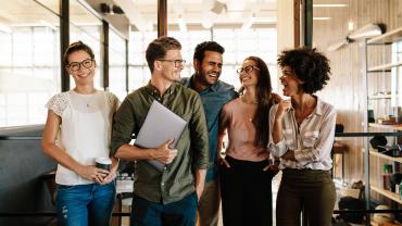Group of diverse professionals chatting in a sunlit office.
