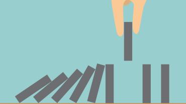 a hand preventing a line of dominoes from collapsing