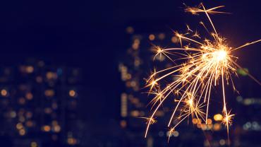 Sparkler lit against a cityscape background