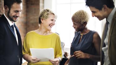 Women and men smiling and discussing options in a business setting