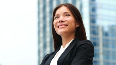 woman in a suit smiling with a faded image of a building in the background