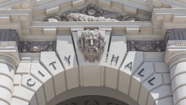 stone façade archway with a Greek face between "city" and "hall"