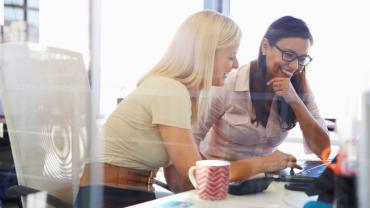 two professional woman seated together at a desk collaborating 