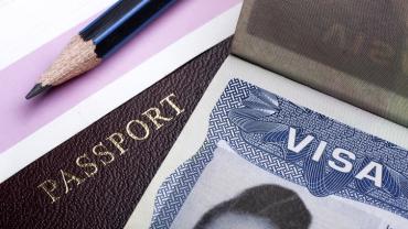 a pencil, passport, and visa are laid out on a table