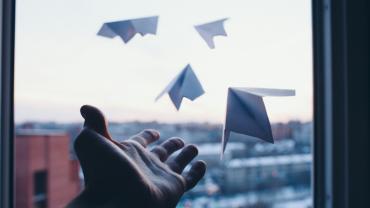 a hand lets go of four paper airplanes