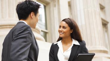 two professionals speaking out side a government building