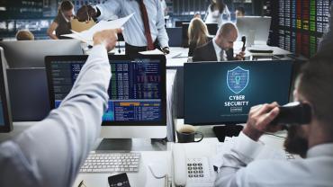 employees working on computers with "cyber security" written on the screen