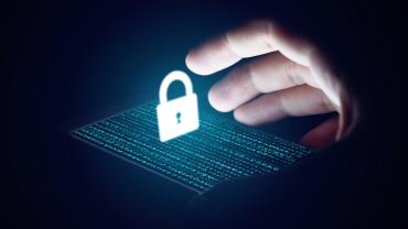 an phone with code on the screen illuminates a hand reaching for a security lock