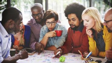 seven diverse professionals gathered around a table during a strategy meeting