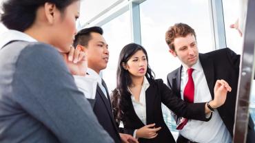 Four professionals standing around discussing a chart