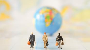 Figures of businesspeople walking toward a globe.