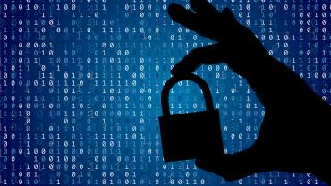 Silhouette of hand holding a lock in front of a blue background with code.