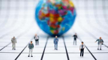 Globe with miniature lawyers standing in front