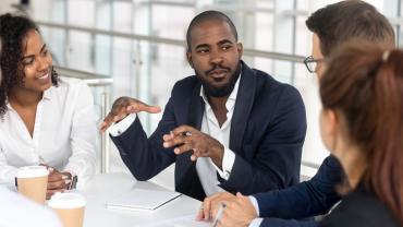 Millennial employees gathered in boardroom for training, black boss leading corporate team during seminar learning at modern office