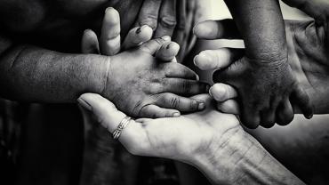 black-and-white of hands holding each other, different skin shades