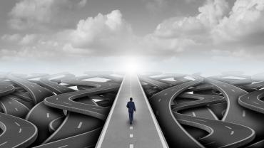  A man in a suit walking on a highway that has many directions. 