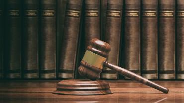 gavel with books, assuming legal books, in background, on shelf-photo