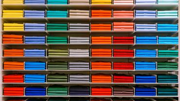 shirts oof many different colors stored in shelves within similar color palettes