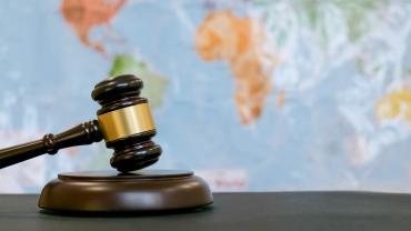 judge's gavel in front of map of the world