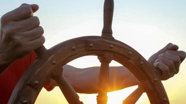 hands, looking white, steering ship's wheel