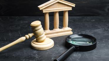 wooden-looking courthouse facade and gavel, magnifying glass