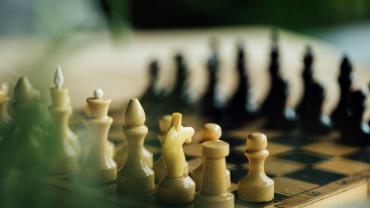 Black and white chess pieces facing each other on chess board. 