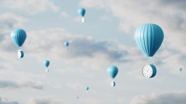 Alarm clocks tied to hot air balloons floating in the sky. 