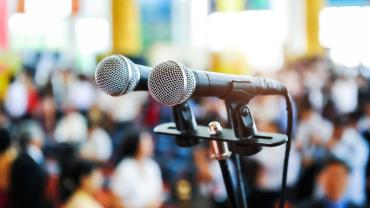 Double microphone in front of a blurred out crowd of people. 