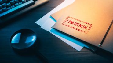 a folder marked confidential and a magnifying glass