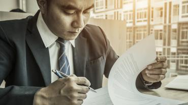 a man in a suit looking at a document and holding a pen