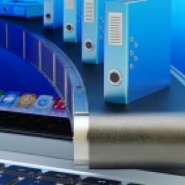 Blue binders on conveyor belt moving from inside a computer screen onto a keyboard.