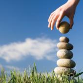 a hand building a stack of stones