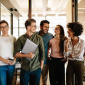 Group of diverse professionals chatting in a sunlit office.
