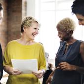 Women and men smiling and discussing options in a business setting
