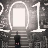man standing at the base of stairs leading into the zero of 2017 written across a chalkboard with symbols such as a computer, money sign, gears, etc.