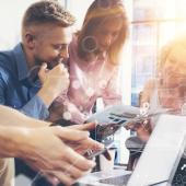 four employees gathered around a computer
