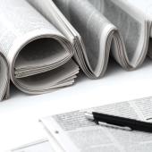 multiple newspapers and a pen on a table
