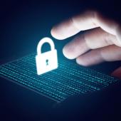 an phone with code on the screen illuminates a hand reaching for a security lock