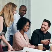 Group of diverse coworkers gathered around a laptop.