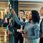 Group of diverse employees using colorful sticky notes in a bright office.