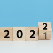 Wood blocks that spell out 2021 turning over to 2021 in front of a light blue background.