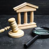 wooden-looking courthouse facade and gavel, magnifying glass